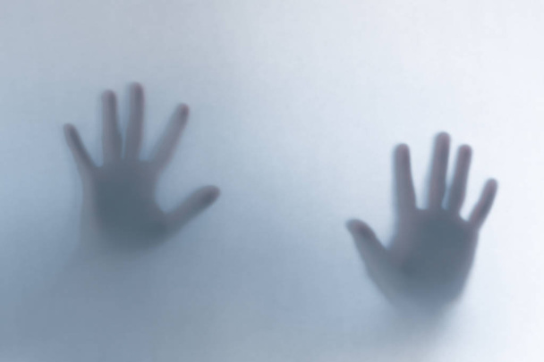 Defocused scary ghost hands behind a white glass background - Valokuva, kuva