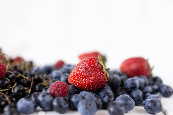 reife Beeren Erdbeeren, Blaubeeren, Himbeeren und Johannisbeeren auf einem weißen Tisch. köstliche Sommerbeeren - Foto, Bild