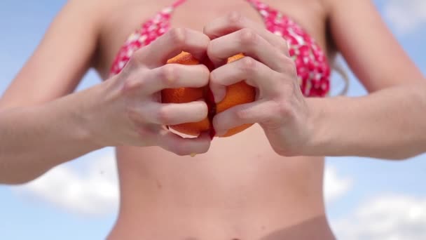 Nainen avoimessa uimapuvussa puristamassa sitrushedelmiä käsin
 - Materiaali, video