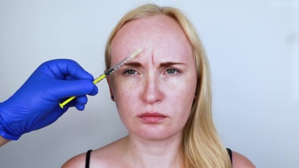 Inyección de Botox en la frente, retire la arruga vertical. Mujer joven en recepción en el esteticista, el procedimiento de rejuvenecimiento
 - Metraje, vídeo