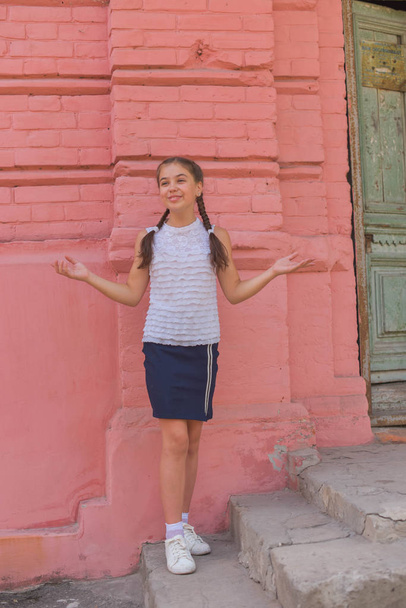 close up portrait of little beautiful stylish kid girl near red brick wall as background - Photo, image