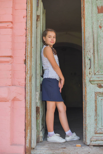 close up portrait of little beautiful stylish kid girl near red brick wall as background - Photo, Image