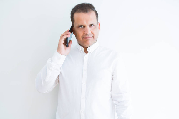 Middle age man calling using smartphone with a confident expression on smart face thinking serious - Фото, изображение