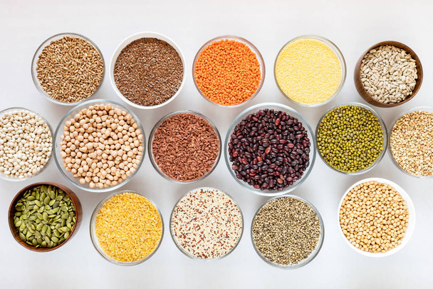 Top view to set of glass bowls with good for health cereals, beans and seeds on white background. - Photo, image
