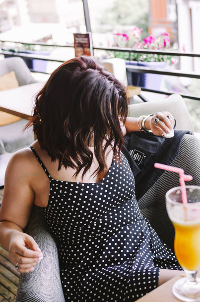 candid woman in polka dot dress drinking cocktail in cafe  - Foto, Bild