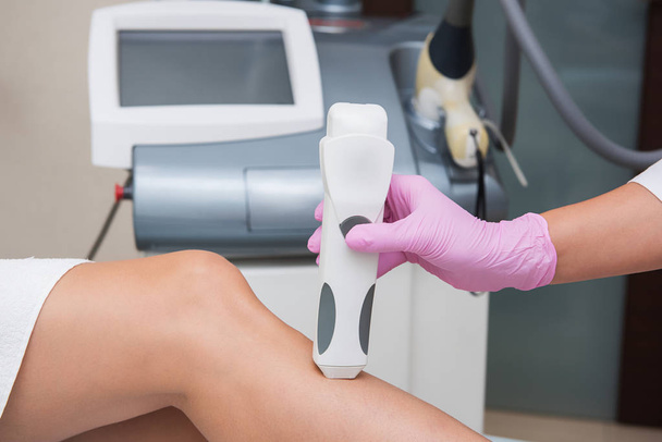 Специалист делает измерения тонуса кожи на женской ноге
 - Фото, изображение