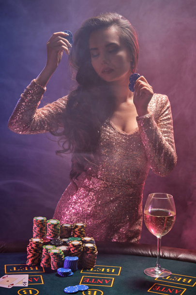 Brunette meisje met een perfecte kapsel en heldere make-up poseert met gokchips in haar handen. Casino, poker. - Foto, afbeelding
