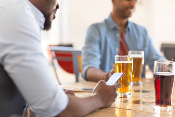 man with smartphone drinking beer at bar or pub - Photo, Image