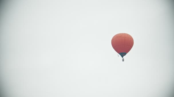 白い空を背景に飛ぶオレンジ色の気球 - 映像、動画