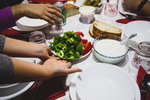 Woman hands serving dishes on the table with red and green peppe - Photo, Image