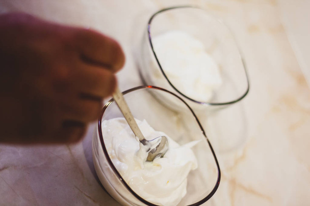 Hand putting cream on transparent bowl - Photo, image