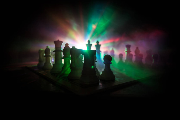 Hra na šachovnici s obchodními nápady a konkurencí. Šachové postavy na tmavém pozadí s kouřem a mlhou. - Fotografie, Obrázek