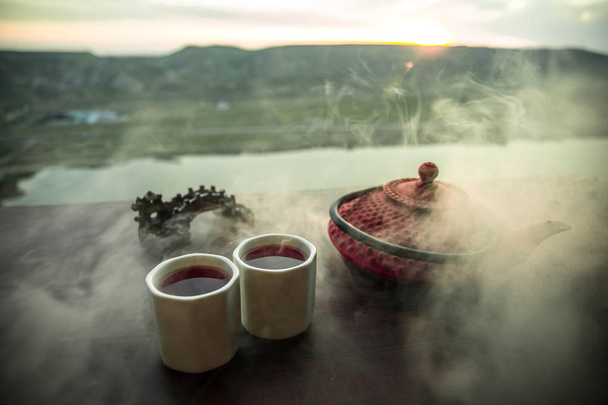 Concetto tè. Cultura cerimonia del tè giapponese bevanda orientale. Teiera e tazze sul tavolo con foglie di bambù al tramonto
 - Foto, immagini