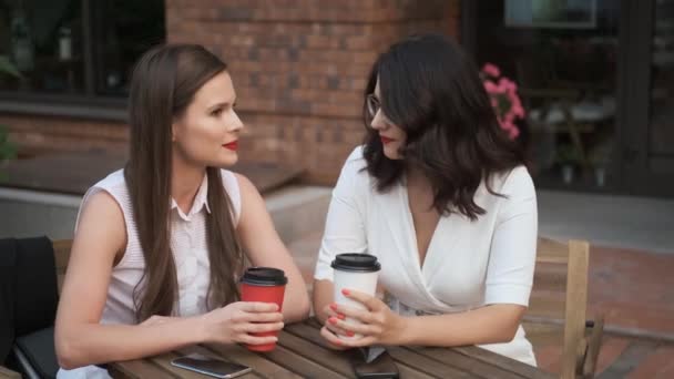 colleagues talk over a cup of coffee. business women sitting in a summer cafe and talking. - Footage, Video