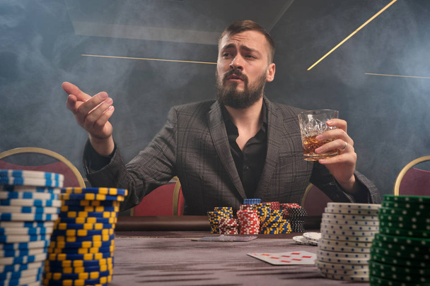 Jóképű szakállas férfi pókerezik az asztalnál a kaszinóban. - Fotó, kép