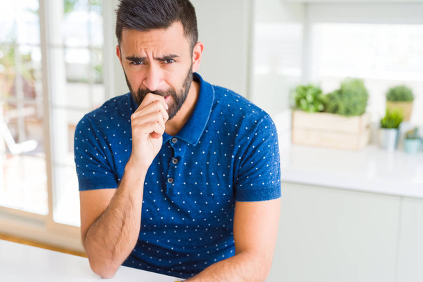 Hombre hispano guapo en casa buscando estresado y nervioso con las manos en la boca mordiendo las uñas. Problema de ansiedad
. - Foto, imagen