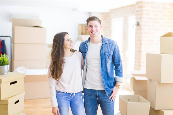 Красивая молодая пара переезжает в новый дом, стоит на новой квартире вокруг картонных коробок, обнимаясь улыбаясь счастливой и влюбленной
 - Фото, изображение