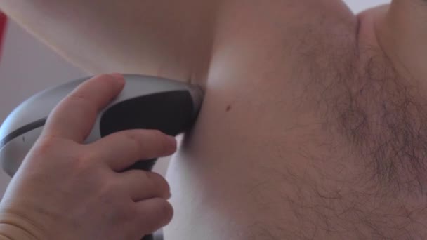  A man uses a laser epilator for epilation at home. Photoepilation of armpit. - Video, Çekim