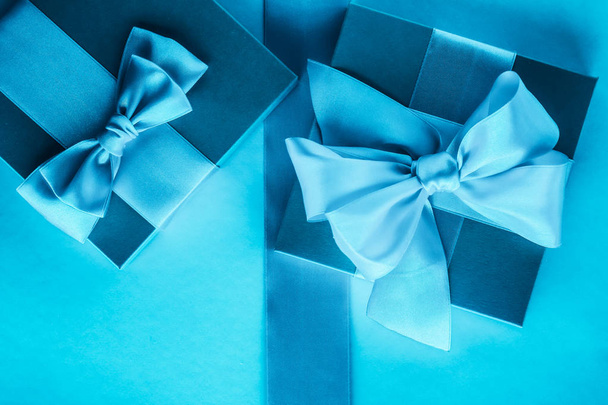 Mavi arka planda ipek şerit ve yay ile lüks tatil hediyeleri - Fotoğraf, Görsel