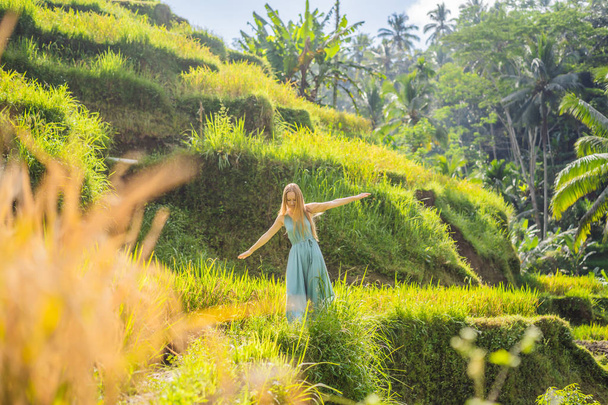 Beautiful young woman walk at typical Asian hillside with rice farming, mountain shape green cascade rice field terraces paddies. Ubud, Bali, Indonesia. Bali travel concept - Foto, immagini