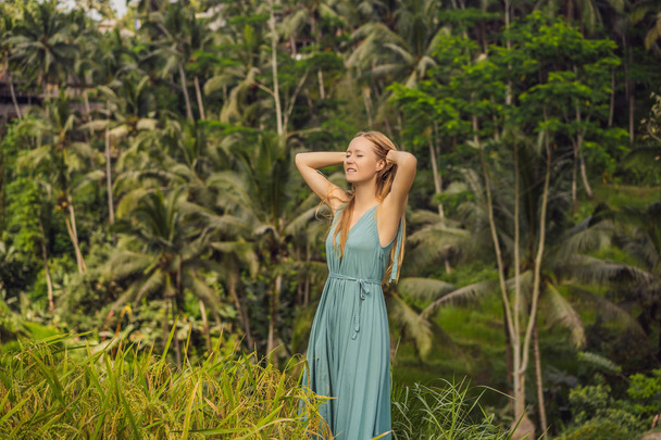 Beautiful young woman walk at typical Asian hillside with rice farming, mountain shape green cascade rice field terraces paddies. Ubud, Bali, Indonesia. Bali travel concept - Foto, Imagem