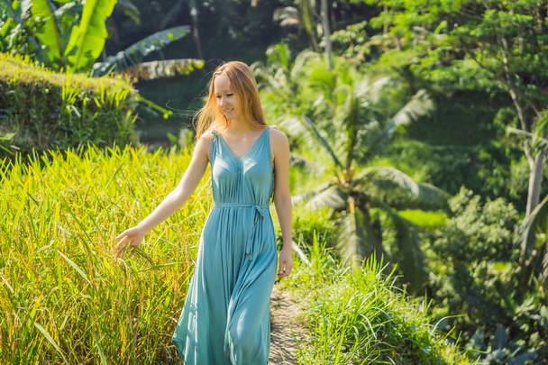 Beautiful young woman walk at typical Asian hillside with rice farming, mountain shape green cascade rice field terraces paddies. Ubud, Bali, Indonesia. Bali travel concept - Фото, изображение