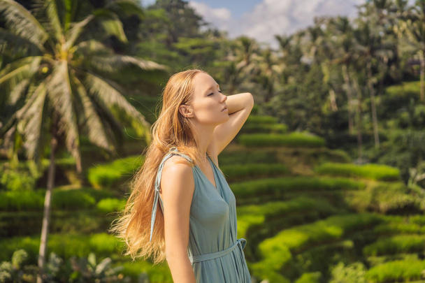 Beautiful young woman walk at typical Asian hillside with rice farming, mountain shape green cascade rice field terraces paddies. Ubud, Bali, Indonesia. Bali travel concept - Fotoğraf, Görsel