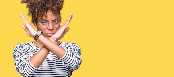 眼鏡をかけてマイナス記号、怒った顔をして孤立した背景除去式交差腕の上の美しい若いアフリカ系アメリカ人女性 - 写真・画像
