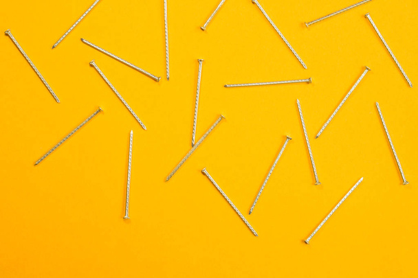 Metal nails isolated on yellow background. working tools - Fotó, kép