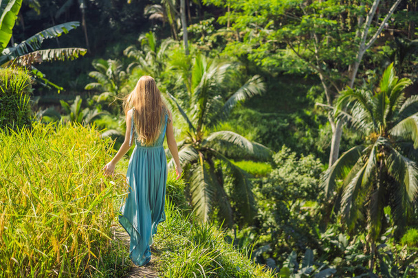 Beautiful young woman walk at typical Asian hillside with rice farming, mountain shape green cascade rice field terraces paddies. Ubud, Bali, Indonesia. Bali travel concept - Photo, Image
