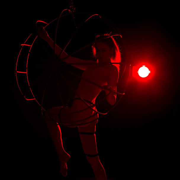 silhouette of sexy female dancer in red light on a dark background. leggy woman in a bodysuit with metal rings. night club concepte - 写真・画像