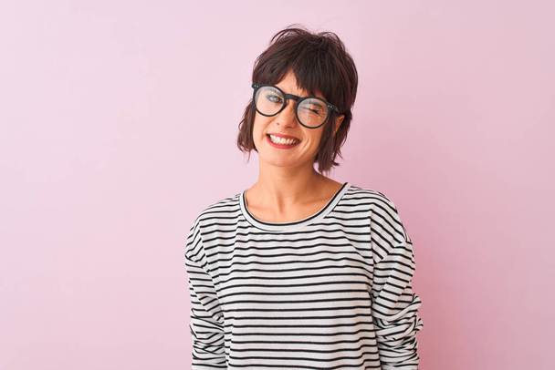 Jovem mulher bonita vestindo listrado t-shirt e óculos sobre isolado fundo rosa piscando olhando para a câmera com expressão sexy, rosto alegre e feliz
. - Foto, Imagem