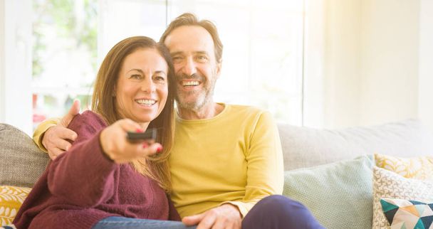 Para romantyczny średnim wieku oglądanie tv na kanapie w domu - Zdjęcie, obraz