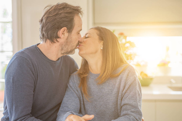 romantisches Paar mittleren Alters sitzt zusammen und küsst sich zu Hause - Foto, Bild