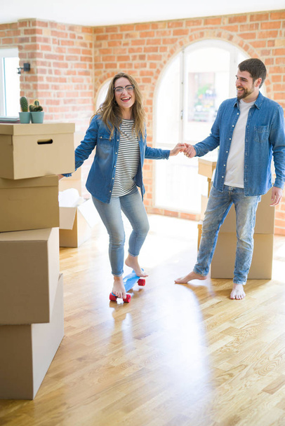 Young couple moving to a new home, having fun riding a skateboard  - Photo, Image