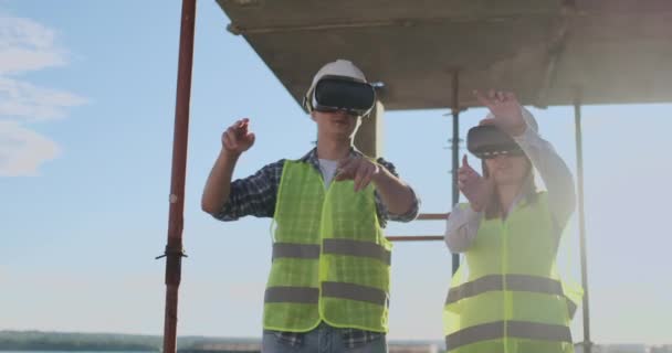 Egy férfi és egy nő mérnökei egy építkezésen VR szemüveg kezelése építése egy épület megvitatása a fejlesztési terv. - Felvétel, videó