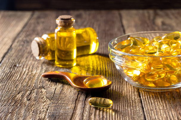 Fish oil capsules on wooden background, vitamin D supplement - Foto, imagen