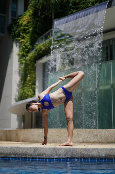 Asian Chinese female Yogi practising by the swimming pool - Foto, immagini