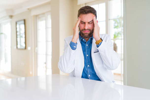 診療所で医療コートを着たハンサムな医者の男性は、ストレスのために頭の痛みのために頭の上に手を置いています。苦しむ片頭痛. - 写真・画像
