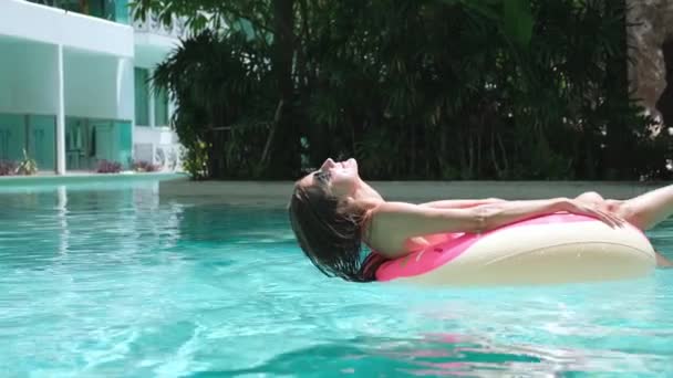 Gelukkige vrouw en opblaasbare zwemmen ring in de vorm van een donut in het zwembad. - Video