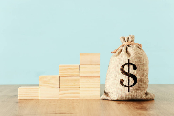business image of a sack with money over wooden desk - Foto, imagen