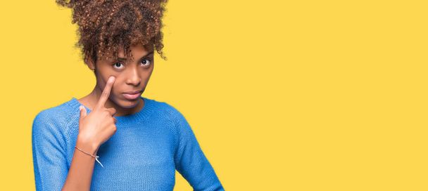 schöne junge afrikanisch-amerikanische Frau über isolierten Hintergrund zeigt auf das Auge beobachten Sie Geste, misstrauischer Ausdruck - Foto, Bild