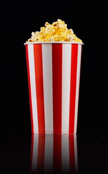 Paper striped bucket with popcorn isolated on black background - Zdjęcie, obraz