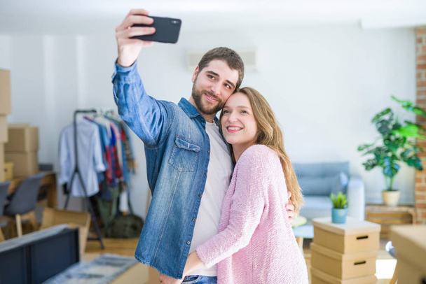 Young beautiful couple taking a selfie photo using smartphone smiling very happy for moving to a new home - Photo, image