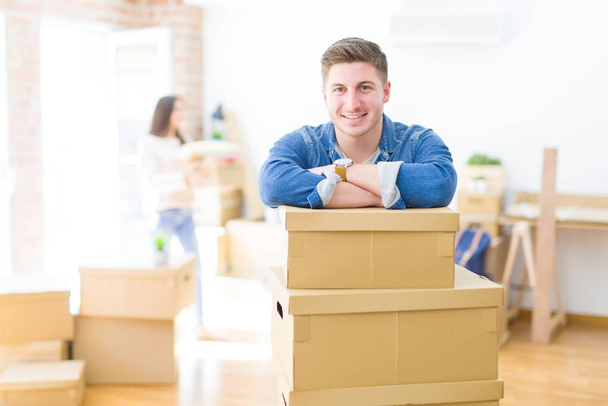 Beautiful young couple moving to a new home, standing on new apartment with cardboard boxes - Photo, Image