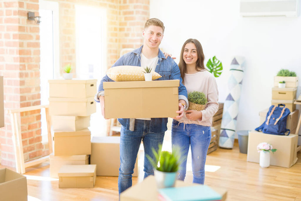 Красивая молодая пара переезжает в новый дом, стоит на новой квартире с картонными коробками
 - Фото, изображение