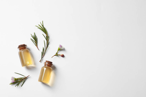 Flat lay composition with bottles of natural tea tree oil on white background - Фото, изображение