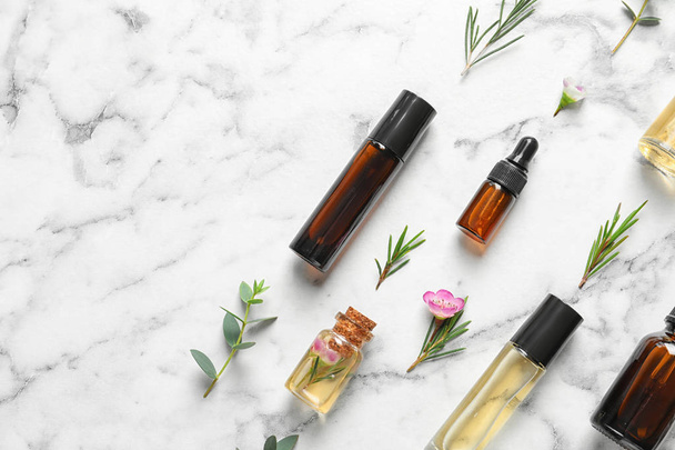 Flat lay composition with bottles of natural tea tree oil and space for text on white marble background - Zdjęcie, obraz