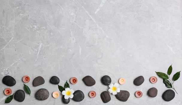 Flat lay composition with spa stones and lit candles on grey marble background, space for text - Φωτογραφία, εικόνα