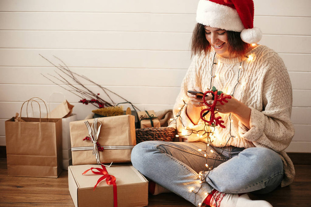 stilvolle glückliche Mädchen mit Weihnachtsmann Blick auf Handy-Bildschirm in festi - Foto, Bild